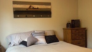 Ein Schlafzimmer mit einem Bett, einem Holzkopfende, einem Schminktisch und einem Wandregal.