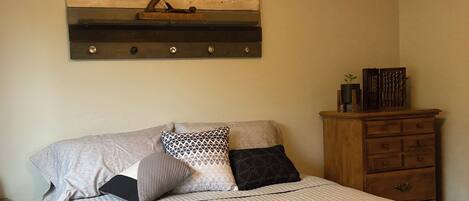 Een slaapkamer met een bed, een houten hoofdbord, een dressoir en een wandplank.