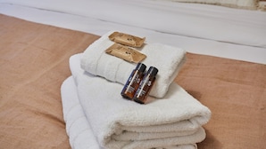 A neatly folded white towel with two small brown packages and two brown bottles on top. - Charming Studio Centre de Paris-montorgueil (Paris)