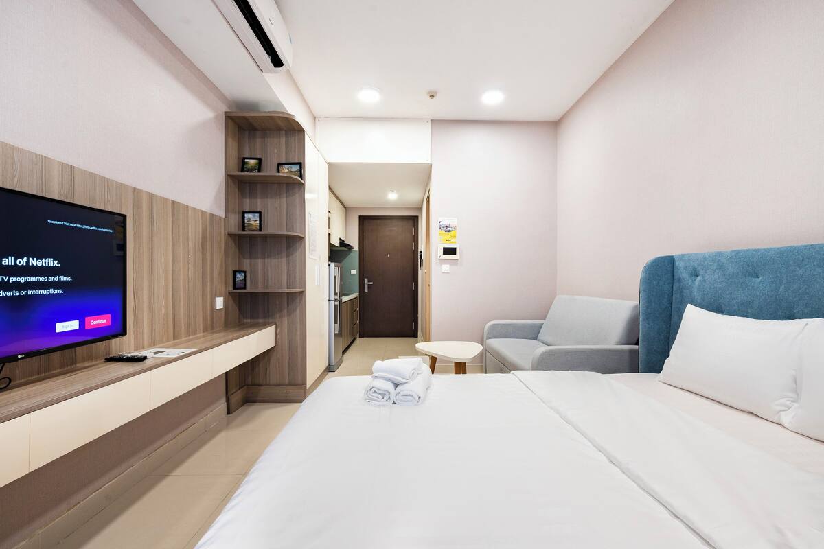 Een hotelkamer met een bed, een televisie op een houten plank, een sofa en een kleine tafel.