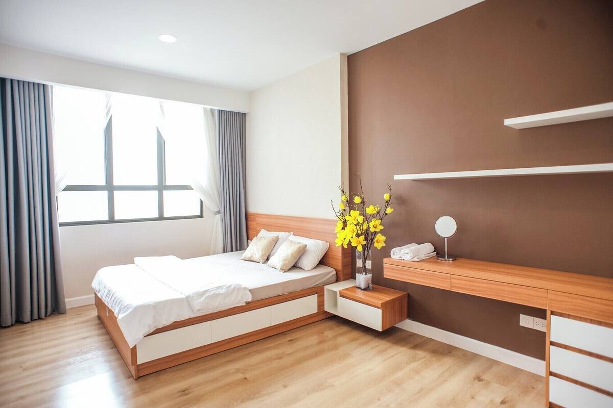 Een moderne hotelkamer met een bed, nachtkastje en een kaptafel met spiegel.
