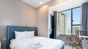 Ett modernt hotellrum med en stor säng, utsikt över en hög byggnad och ett litet bord med en stol.