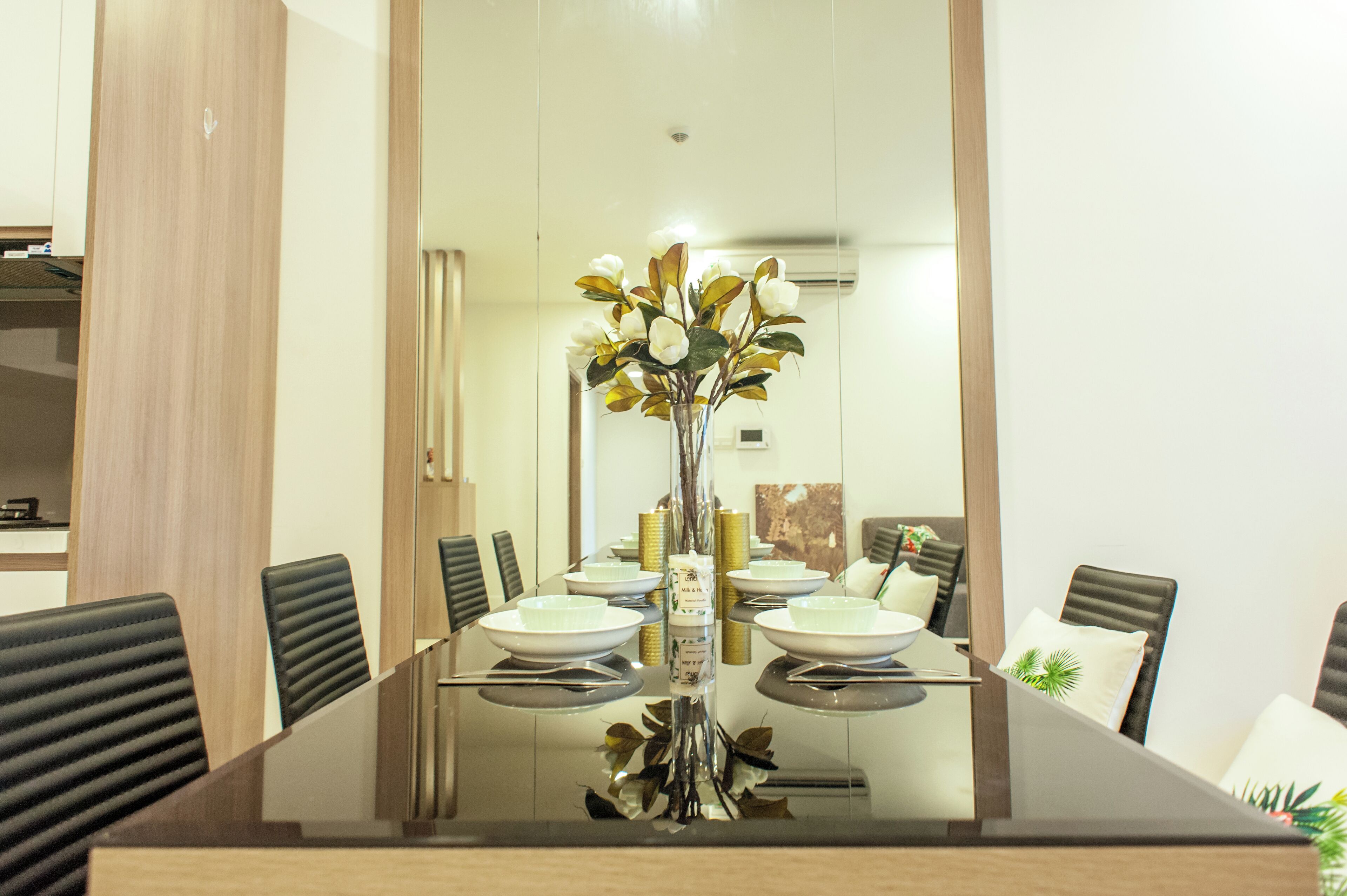 A modern dining area with a glass table, black chairs, and a vase with flowers.