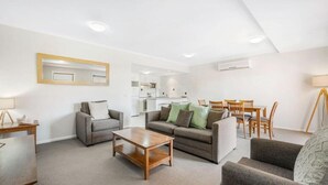 Uma sala de estar moderna com um conjunto de sofá, uma mesa de centro e um espaço de jantar com cadeiras.