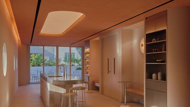 Una cocina moderna con una isla central, taburetes de bar y estanterías integradas.