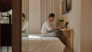 A bedroom with a bed, a desk, and a mirror.