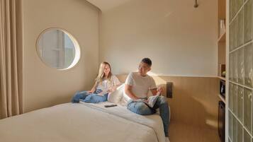 A bedroom with a bed, a round mirror, a bedside table, and a nightstand.