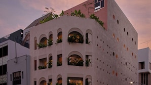 Un edificio moderno con varios balcones, un jardín en la azotea y un letrero que dice 'KINN HABITAT'.