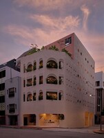 A modern building with multiple balconies, a rooftop garden, and a sign for 'KINN HABITAT'.