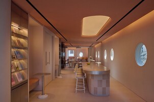 A modern kitchen with a central island, bar stools, and a built-in bookshelf.