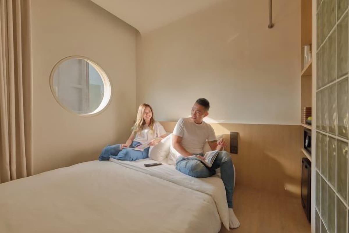 A bedroom with a bed, a round mirror, and a bedside table.