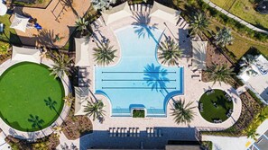 An aerial view of a resort with a central swimming pool, a tennis court, and surrounding palm trees. - Shoreline Sanctuary – Pool • Beach• Downtown• Pickle ball• Putting Green (St. Augustine)