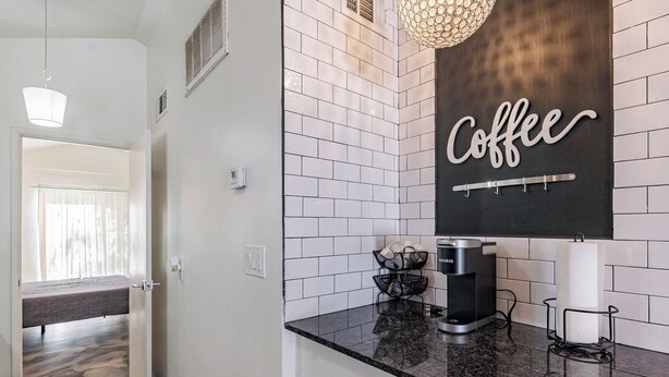 A modern kitchen with white subway tiles, a coffee sign, a coffee machine, and a hanging light fixture.