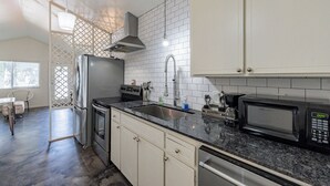 A modern kitchen with white cabinets, a stainless steel refrigerator, a microwave, and a sink.