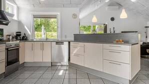 A modern kitchen with a large island, stainless steel appliances, and pendant lighting.