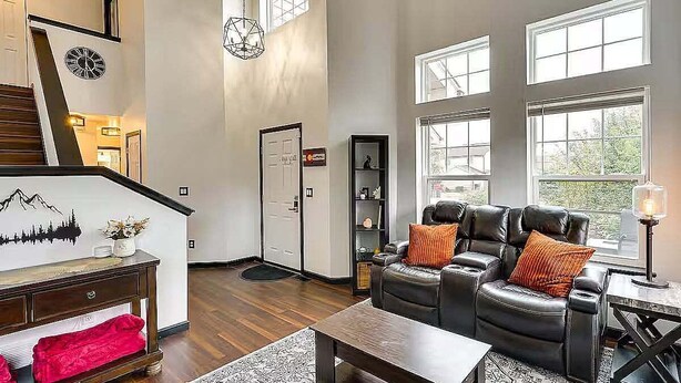 A spacious living room with a leather sofa, a coffee table, and a staircase with a clock. - Relax at Fountain: Hot Tub Fun (Fountain)