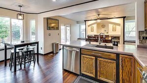 A modern kitchen with a central island, bar stools, and a view of the dining area. - Relax at Fountain: Hot Tub Fun (Fountain)