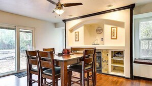 A dining area with a wooden table and chairs, a ceiling fan, and a fireplace with shelves. - Relax at Fountain: Hot Tub Fun (Fountain)