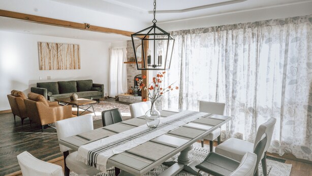 A spacious living room with a large dining table, comfortable seating, and a fireplace. - ClubDivot - A Modern Farm Style  Home with Pool and Backyard Bar (Vineland)