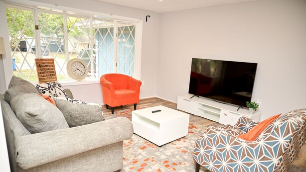 Una sala de estar con un sofá, una mesa de centro, un televisor y un tapete estampado.