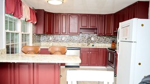 Una cocina con armarios rojos, un refrigerador blanco y un salpicadero de azulejos.