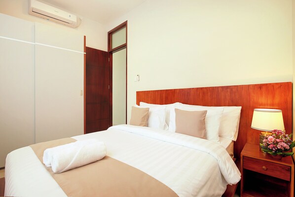 A hotel room with a bed, a nightstand with a lamp, and a wardrobe.