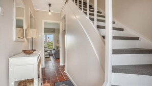 A hallway with a white console table, a lamp, a doormat, and a staircase with gray steps. - Haus Hildebrand - "Relax and feel good in Haus Hildebrand!" (Hörnum)