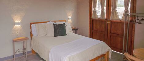 A bedroom with a wooden bed, two bedside tables, a hanging light fixture, and a wooden wardrobe with curtains.
