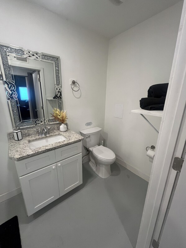 Et badeværelse med en hvid vask, toilet og et spejl med dekorativ ramme.