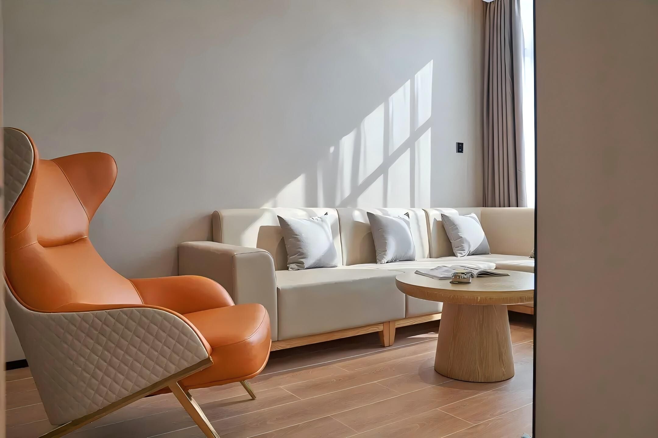 A modern living room with a leather armchair, a sofa with multiple cushions, and a wooden coffee table.