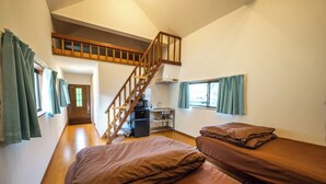 A dormitory room with two single beds, a wooden staircase, a kitchenette, and a window with curtains. - CORAZON RESORT (Minamidaito)