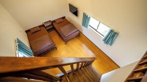 A room with two beds, a TV mounted on the wall, and a window with curtains. - CORAZON RESORT (Minamidaito)