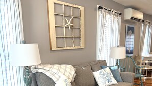 A cozy living room with a grey sofa, a wooden side table, and a decorative wall piece.