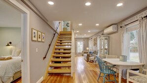 A staircase leading to a dining area with wooden flooring, a dining table, chairs, and a window with curtains.