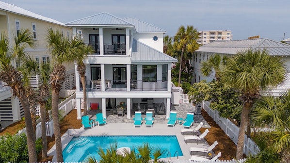 A two-story building with a pool and lounge chairs.