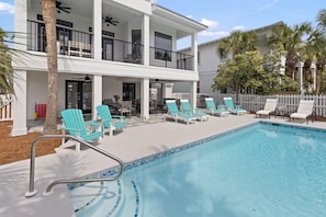 A two-story building with a pool area featuring lounge chairs and a dining table. - Exclusive Gulf-Front Estate w/ Private Beach Access (Destin)