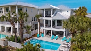 A two-story hotel with a swimming pool, outdoor seating, and palm trees.