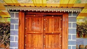 A wooden double door with a decorative trim, leading to a set of stairs. - Madhura Agro Tourism (Wai)