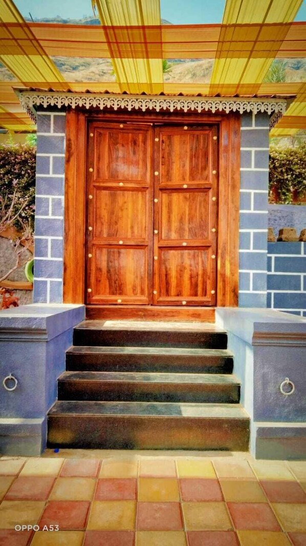 A wooden double door with a decorative trim, leading to a set of stairs. - Madhura Agro Tourism (Wai)