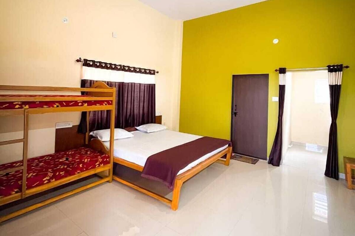 A room with bunk beds, a bed, a ceiling fan, and a door.