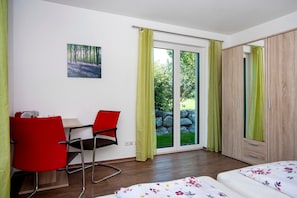 Une chambre à coucher comprenant un lit, un bureau avec une chaise, une armoire et une porte-fenêtre coulissante donnant sur un espace extérieur.