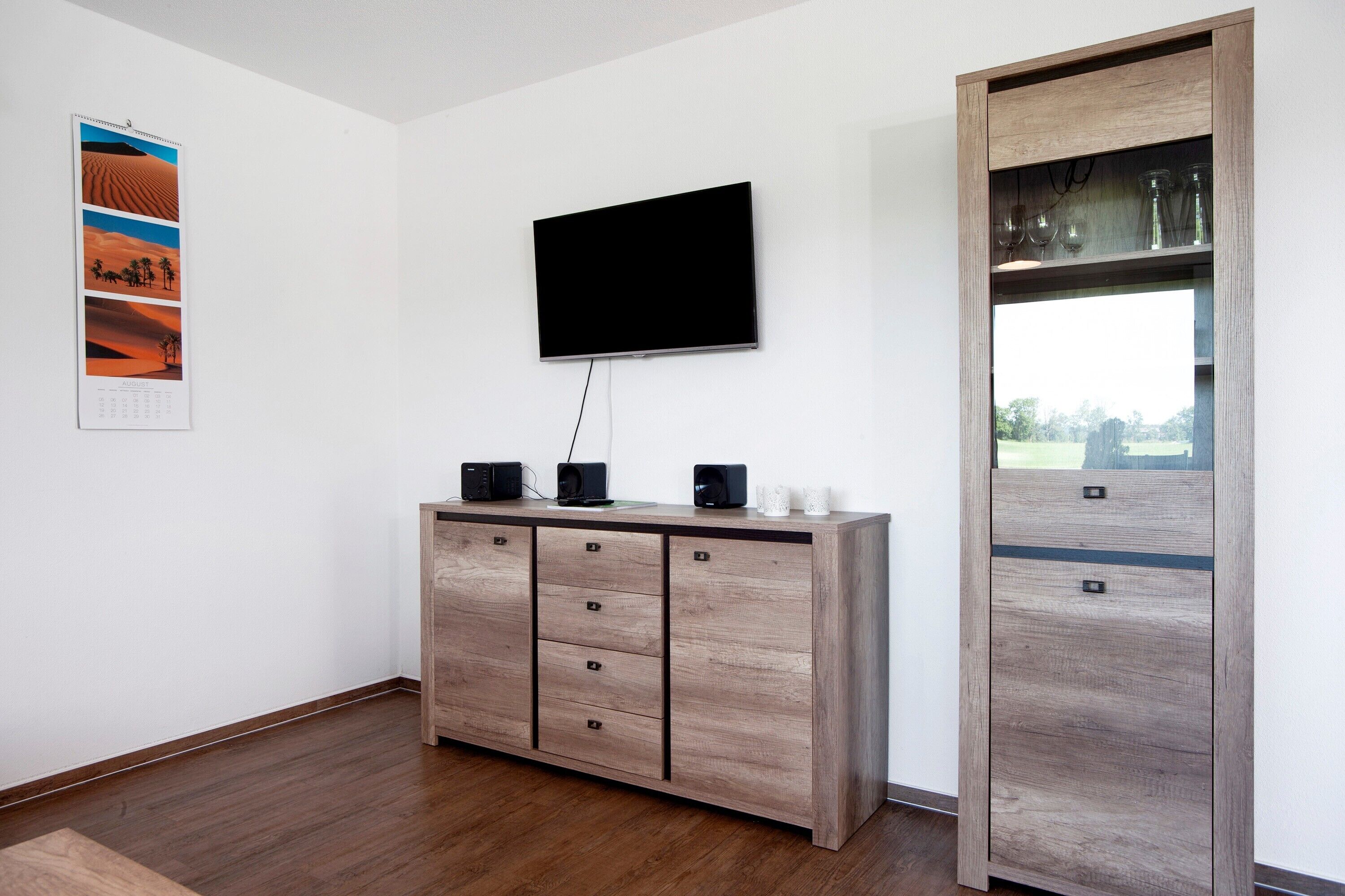 Ein Zimmer mit einem Holzkasten, einem Wandfernseher und einer Glastür mit Blick.