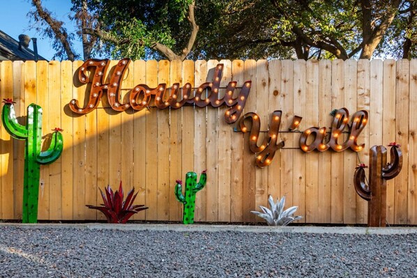 A wooden fence with the sign "Howdy Jilly" and decorative cacti.
