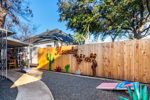 A wooden fence with a sign that reads "Howdy Y'all" and decorative cacti. - Huge 5BR compound! Walk to downtown & Rainey St. (Austin)