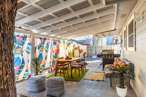 A covered patio with a dining table, chairs, a grill, and a colorful fence. - Huge 5BR compound! Walk to downtown & Rainey St. (Austin)