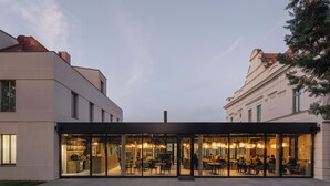 A modern building with a glass facade and outdoor seating area. - Hotel Villa Fitz (Rokycany)