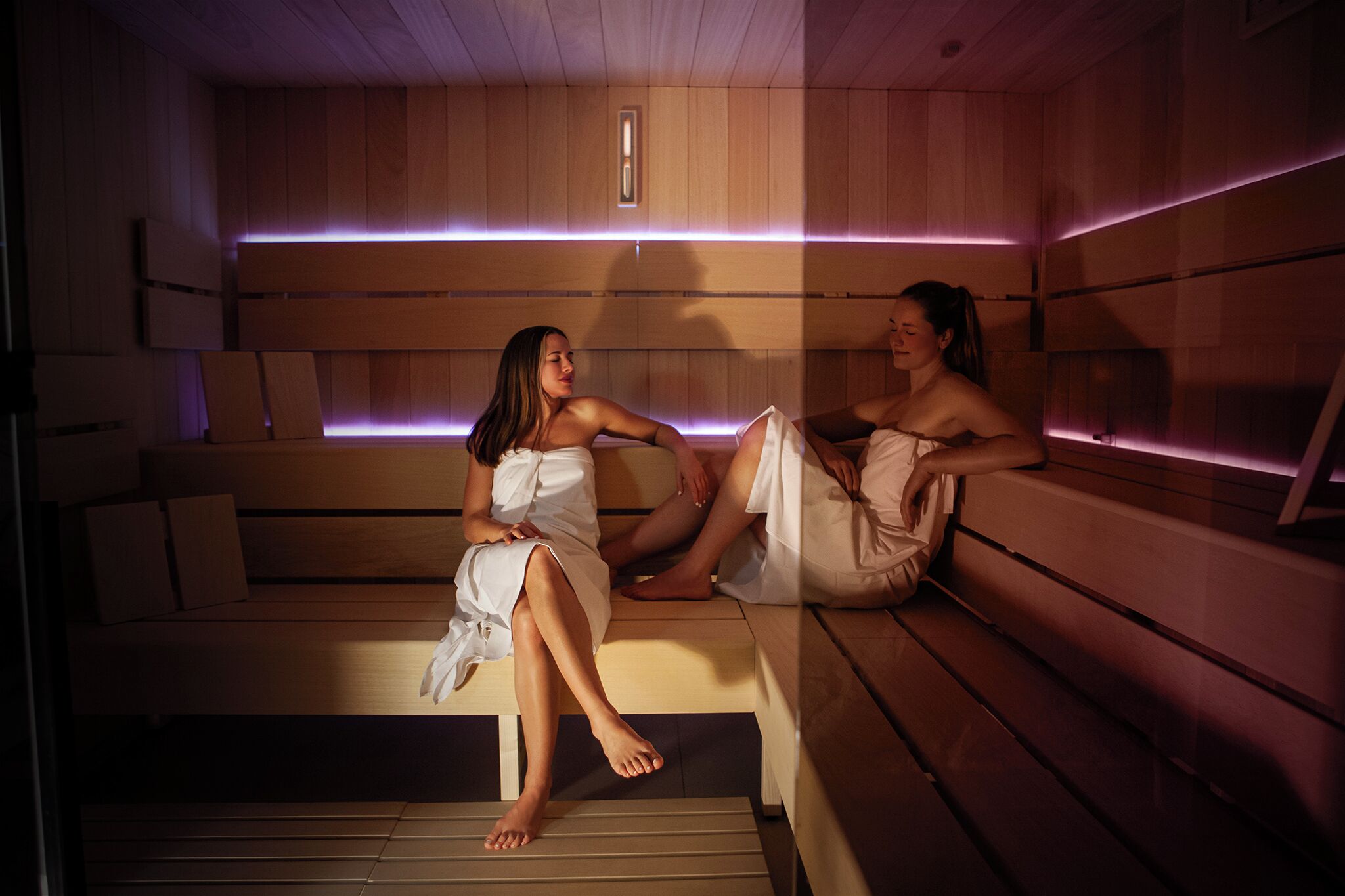 Una sauna con bancos de madera y un aplique central.