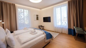 A modern hotel room with a large bed, a flat-screen TV, a desk, and a chair. - Hotel Villa Fitz (Rokycany)