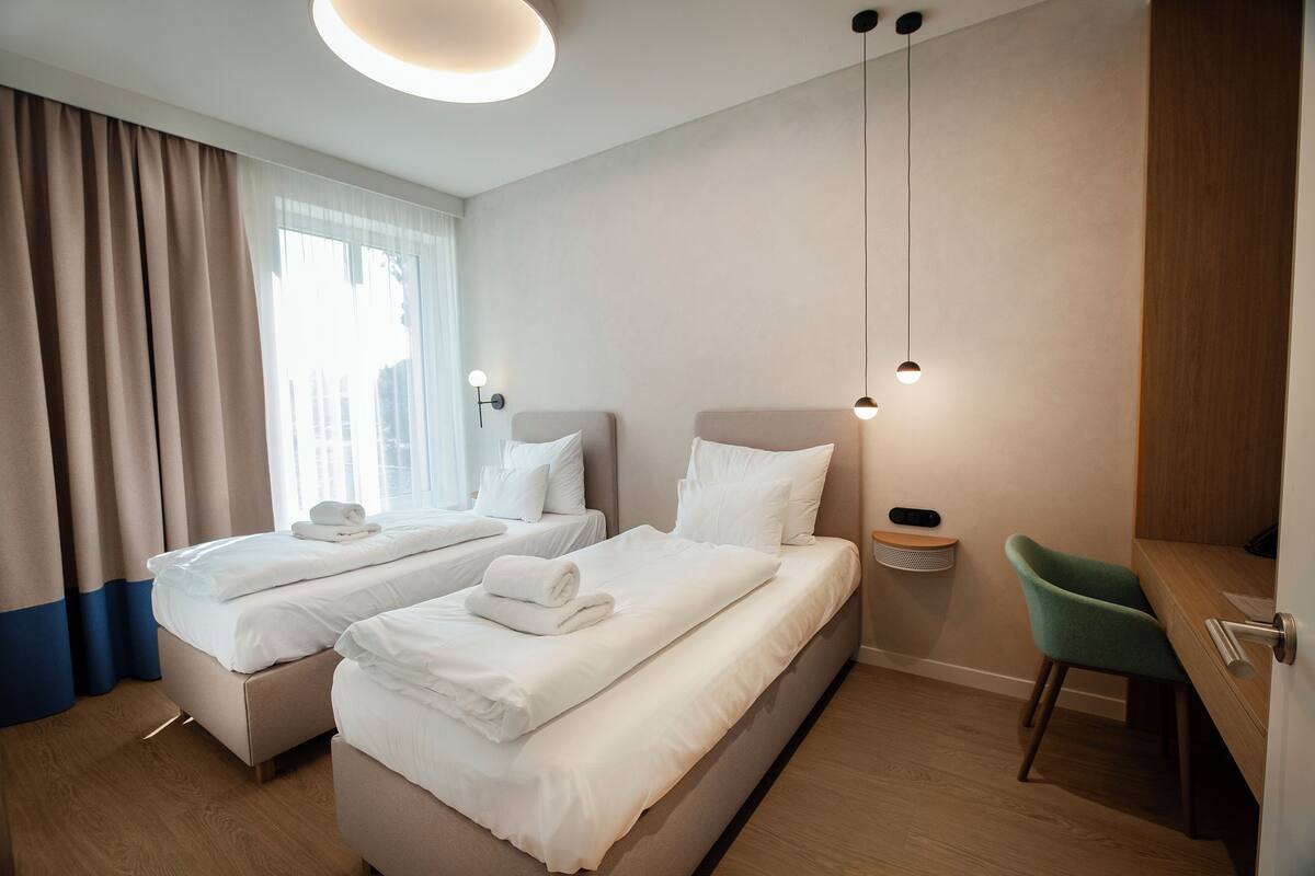 Ein Hotelzimmer mit zwei Betten, einem Schreibtisch, einem Stuhl und einem Nachttisch.