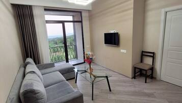 Una sala de estar moderna con un sofá gris, una mesa de centro de vidrio y un televisor montado en la pared.
